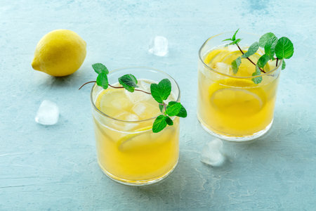 Glasses of lemonade, a mocktail with lemon juice, on a blue background, summer cold drink, with fresh mintの写真素材