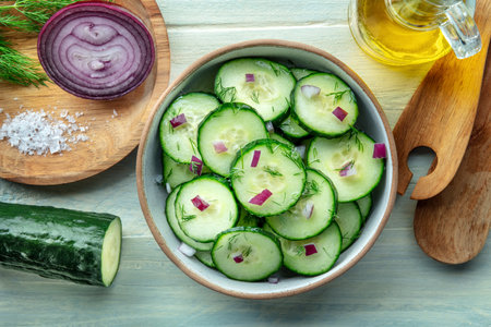 Cucumber salad with olive oil, dill, and red onion, overhead flat lay shot on a rustic wooden table, cooking with fresh vegetablesの写真素材