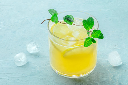 A glass of lemonade, a mocktail with lemon juice, on a blue background, summer cold drink, with fresh mintの写真素材