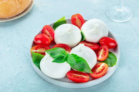 Buffalo Mozzarella, fresh cherry tomatoes, and basil leaves, Italian Caprese salad, with wine and breadの写真素材