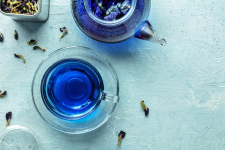 Blue tea, an infusion of butterfly pea flowers. A cup and a teapot, overhead flat lay shot with copy space
