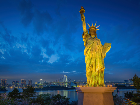 Statue of Liberty and Rainbow bridge, located at Odaiba Tokyo, with Tokyo skyline in background at twilightの写真素材