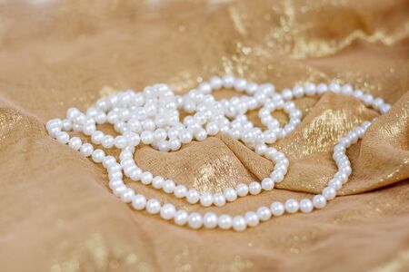 woman white  pearls necklace on gold silkの写真素材