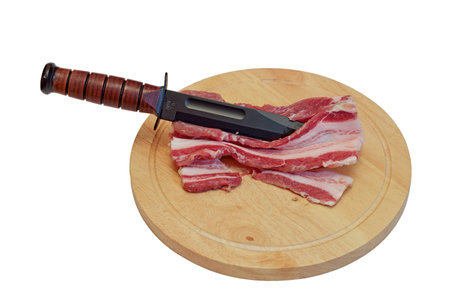 The ham cut on pieces with a fighting dagger on a round board.の写真素材