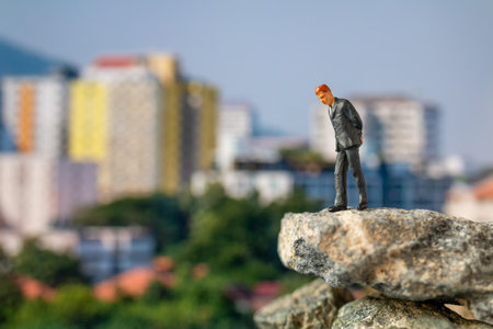 Miniature people , Businessman standing on The rock with building background