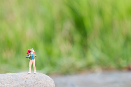 Travel and Adventure concepts. Traveler miniature mini figure with backpack stand and walking on meadow