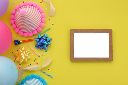 Happy birthday background, Flat lay colorful party decoration with photo frame on pastel yellow background.