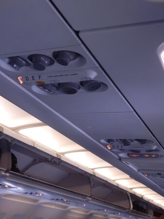 Interior of aircraft cabin showing luggage lockers, air vents and lightsの写真素材