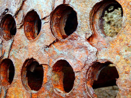 Close up of holes in a rusted perforated metal plate