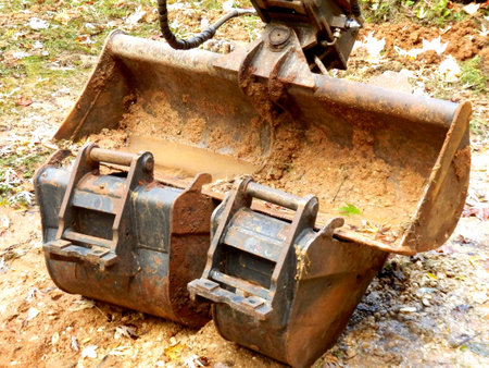 Excavator arm and bucket resting on two smaller buckets