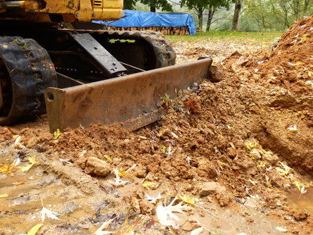 Excavator shovel pushing soil back into a holeの写真素材