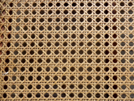 Close up of the pattern formed by open weave rattan cane on a chair seatの写真素材