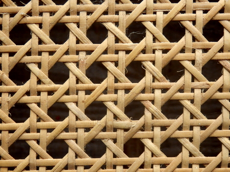 Close up of the pattern formed by open weave rattan cane on a chair seatの写真素材