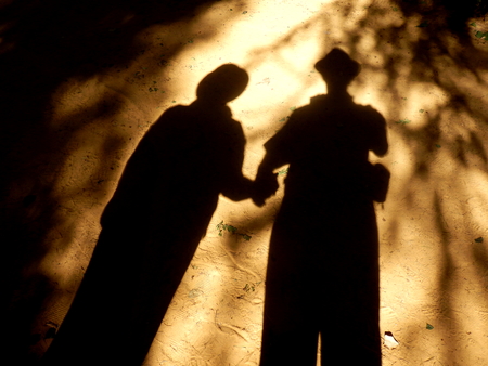 Eerie picture of a shadow couple holding hands on sandy groundの写真素材