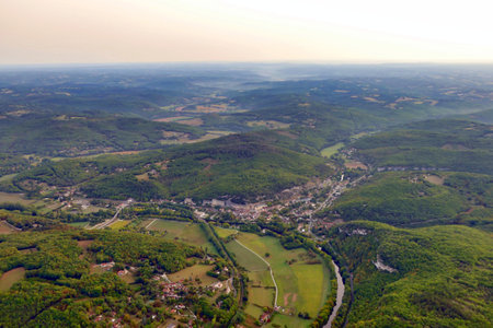 Aerial view of the town of Les Eyzies de Tayac, Dordogne, France, nestled under the shadow of overhanging limestone cliffs, at sunrise as viewed from a hot air balloon following a dawn take off.の写真素材