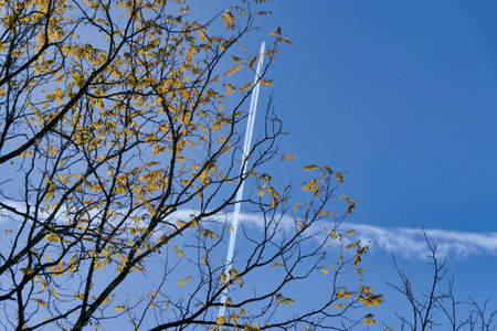Vortex smoke trail from a French military jet aircraft bisecting the smoke trail from another jet aircraft highlighted against a beautiful blue skyの写真素材