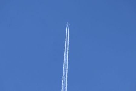 Vortex smoke trail from a low flying jet aircraft bisecting a beautiful blue sky