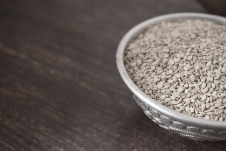 Sesame seeds in a bowl on a wooden table with copy space