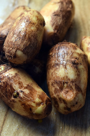 Group Of Unpeeled Taro Root Vegetable On Wooden Table  Imageの写真素材
