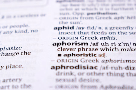 Close Up Of English Dictionary Page With Word - aphorism
