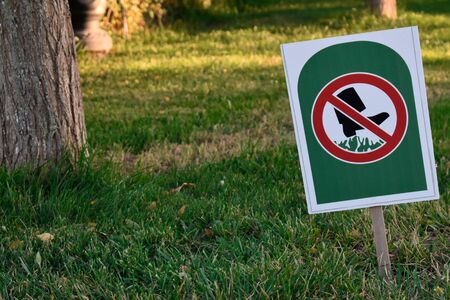 Sign Dont Walk On Grass in public park with trees and grass on green with copy spaceの写真素材