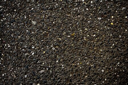 Black asphalt view with inclusion of small golden and white stones - backgroundの写真素材