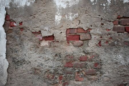 Old ruined wall with sticking out fragments of bricks and cementの写真素材
