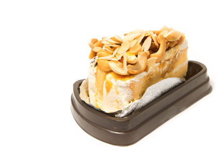 Slice of caramel cream and almonds cake on white background
