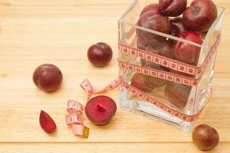 Red plum fruit with measuring tape in glass bowl , Diet fruit for weight lossの写真素材
