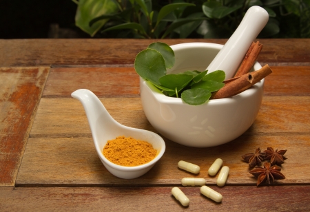 mortar and pestle with herb and pills on wood textureの写真素材