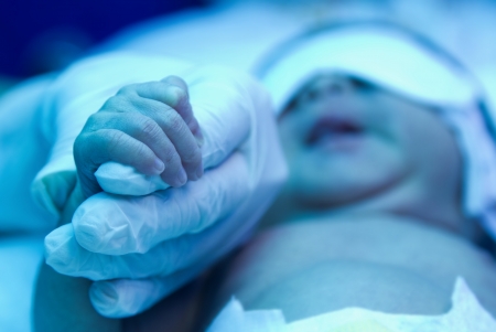 Pediatrician hold baby s hand,under ultraviolet lamp in the incubatorの写真素材