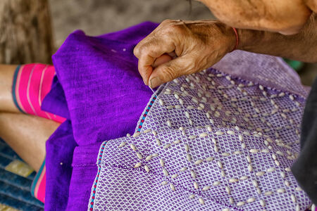 Female hand stitching cloth to make ancient Thai pattern fabricの写真素材