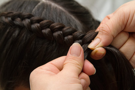 Hairdresser make braids in beauty salon