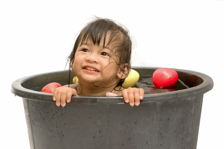little girl playing with water in little plastic bath tabの写真素材