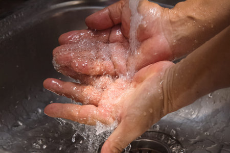 hands being washed under stream of  water from tap