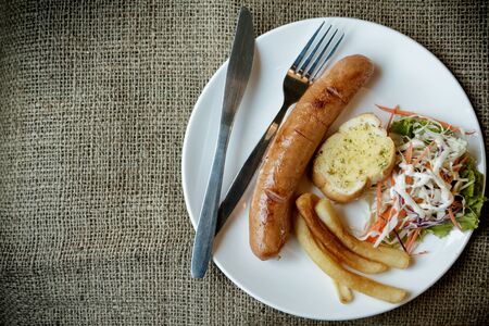 Grilled sausages with salad on white plateの写真素材