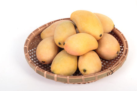 Golden ripe mangoes in basket on white backgroundの写真素材