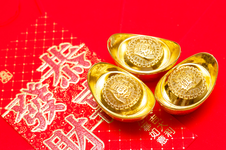 Chinese red envelope and gold ingots  (Yuan Bao) for Chinese new year.(Foreign text means blessing)の写真素材