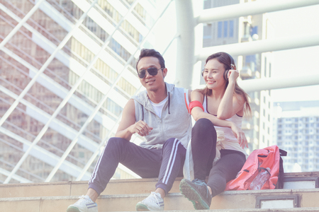 Couple of runners listening to the music with earbuds from a smart phone on urban backgroundの写真素材