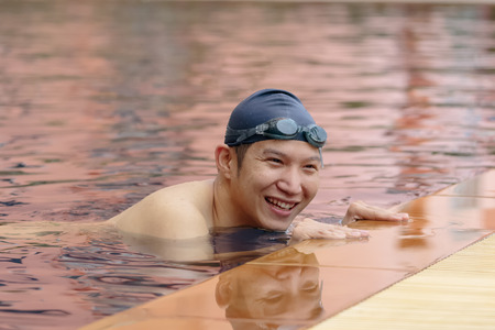 Handsome Asian man wearing swim cap and goggles at the poolの写真素材