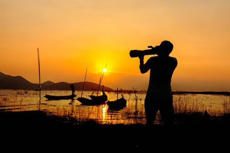 Silhouette of photographer taking pictures of the beautiful moments during the sunsetの写真素材