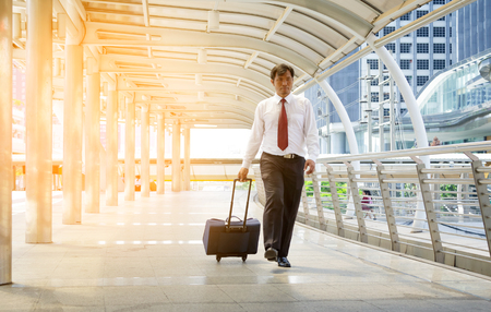 Businessman carrying a suitcase on passage of modern buildingの写真素材