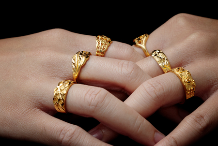 woman's hand with many jewelry rings on black backgroundの写真素材