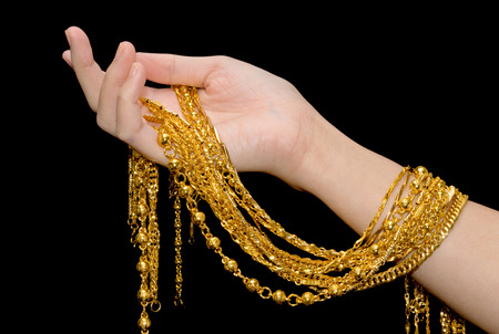 Woman hand holding expensive golden chains on black backgroundの写真素材