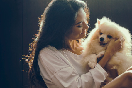 Happy woman embracing the white pomeranian dogの写真素材
