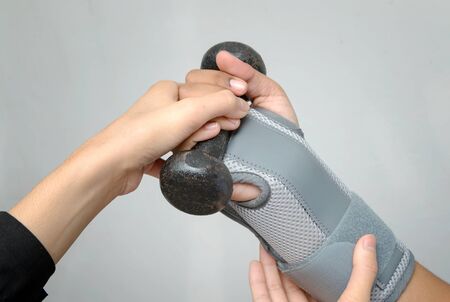 Woman's hand with wrist support lifting dumbbell for hand exercise ,rehabilitation handの写真素材
