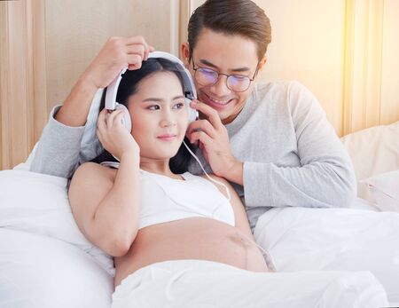 Pregnant woman listening music with her husbandの写真素材