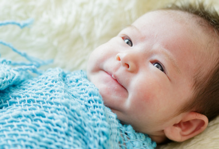 Newborn girl in blue wrap lying on basketの写真素材