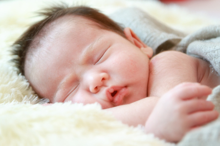 Newborn baby girl is sleeping on fur blanketの写真素材
