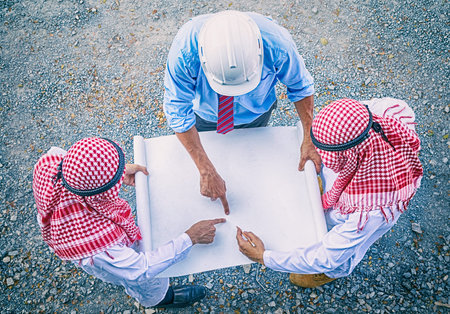Arab businessman and engineers holding papar and discussing about plan of building site constructionの写真素材